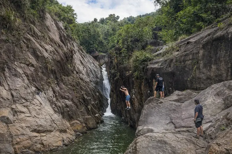Guests climbing the rocks beside a narrow canyon waterfall
