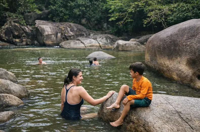 Parent and child sitting at the edge of a calm swimming hole