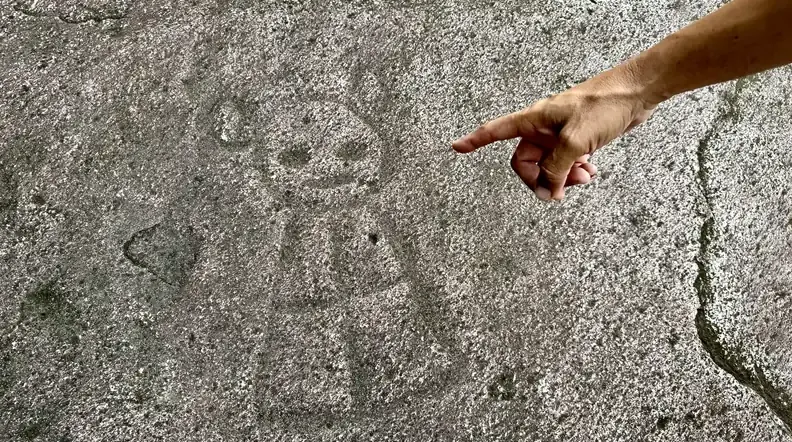 Guide pointing to a Taino petroglyph carved into river rock on the Adventure Expedition