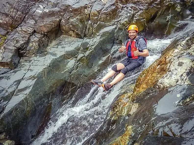 Guest sliding down a natural rock waterslide on the El Yunque waterslides tour